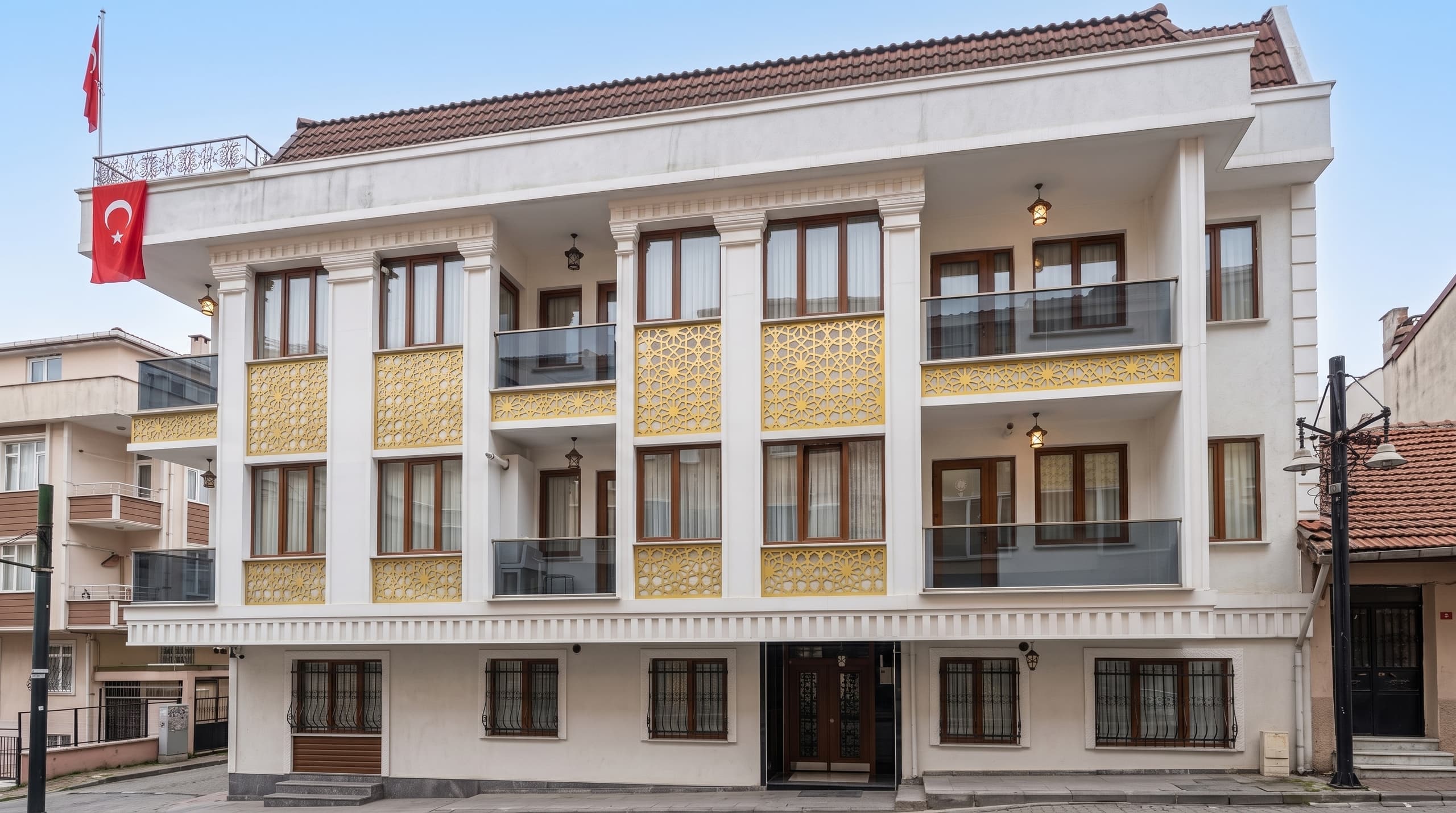 Sarı geometrik cephe süslemeleri ve cam balkon korkulukları olan butik apartman